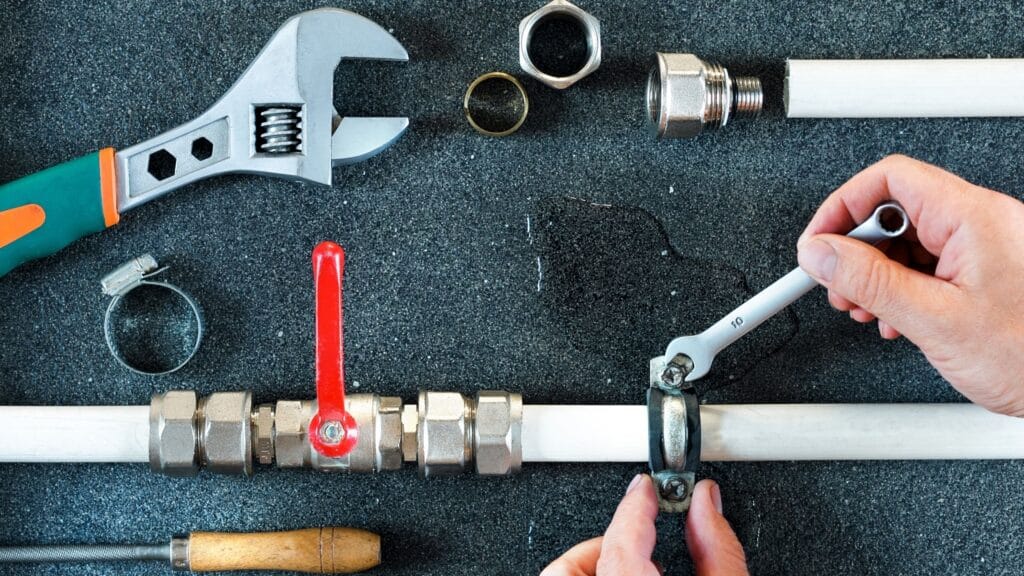 Plumber repairing a pipe valve with an adjustable wrench in Temecula