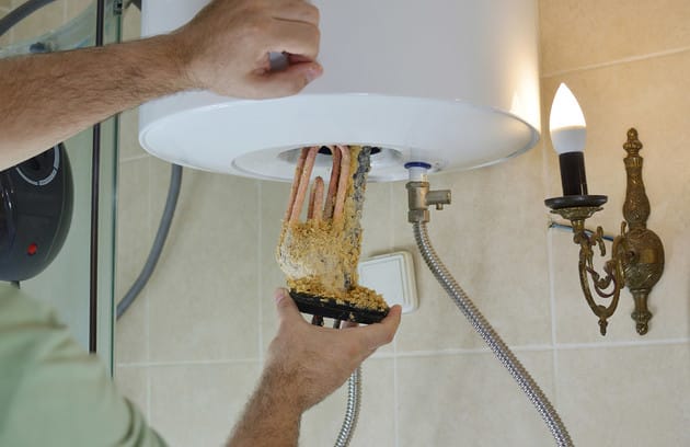 Technician removing mineral buildup from a water heater in Temecula