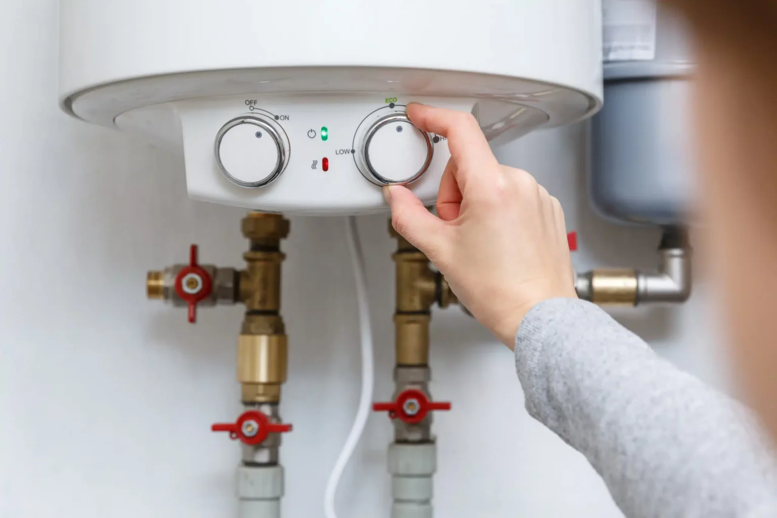 Homeowner adjusting the temperature controls on a water heater in Temecula